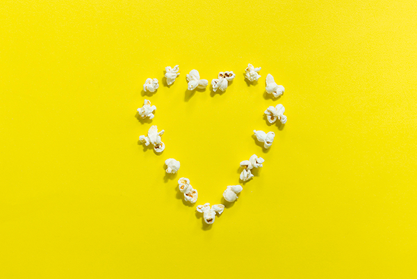 The Best Heart Healthy Snacks on the Go, image of a heart made out in popcorn on a yellow backdrop