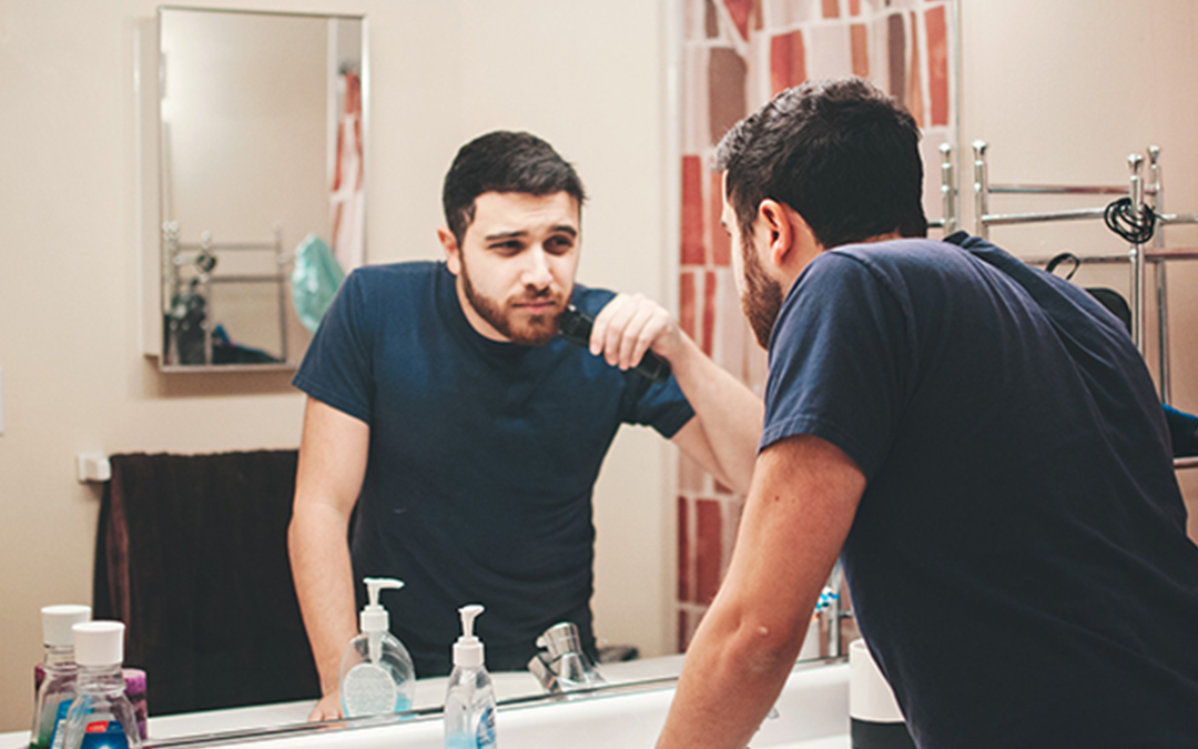 Male Pattern Baldness, image of a man trimming his beard looking in the mirror